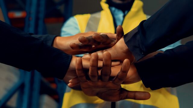 Factory,Workers,Stacking,Hands,Together,In,Warehouse,Or,Storehouse,.