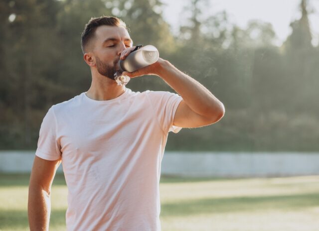 Young sportsman drinking water at stadium