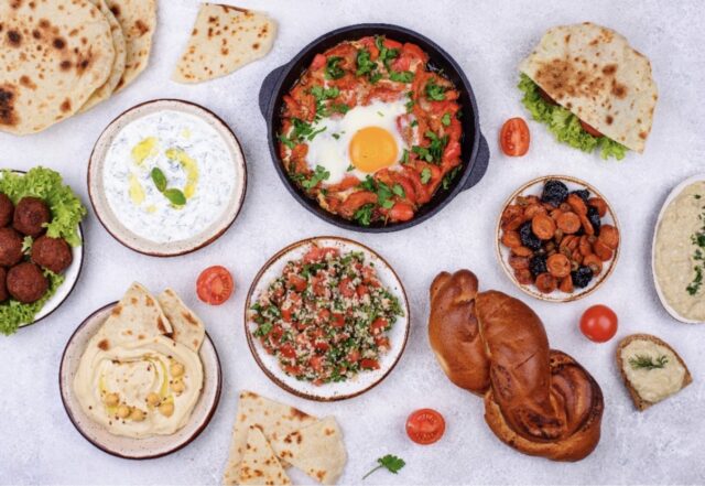 Overhead spread of Middle Eastern dishes including shakshuka, hummus, falafel, flatbreads, tabbouleh, and fresh dips — a vibrant feast reflecting the best hidden restaurants in London locals swear by.