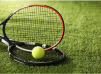 Two tennis rackets and a yellow ball resting on grass, illustrating Wimbledon’s grass-court tradition