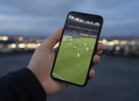 Hand holding a smartphone showing a blurred live sports stream